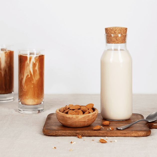 Zwei Gläser Eiskaffee mit einer Flasche Mandelmilch